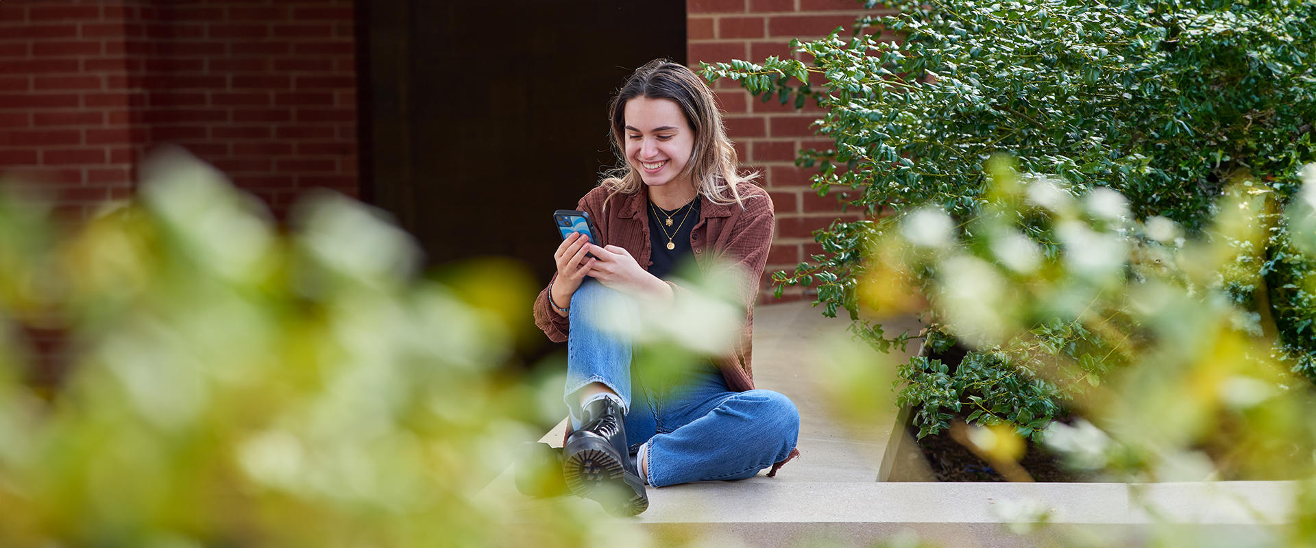 A student checks her phone outside her residence hall